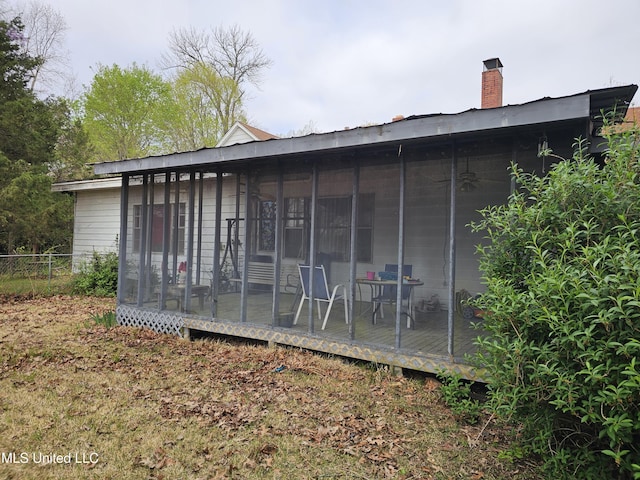 view of outbuilding featuring a sunroom and fence