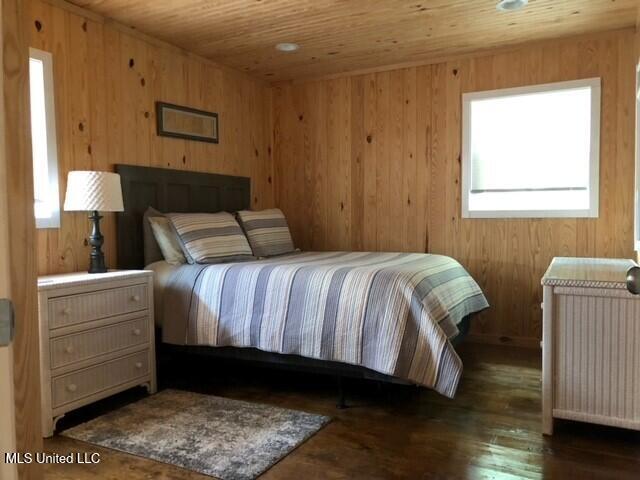 bedroom featuring dark wood-type flooring, radiator, wooden walls, and wood ceiling