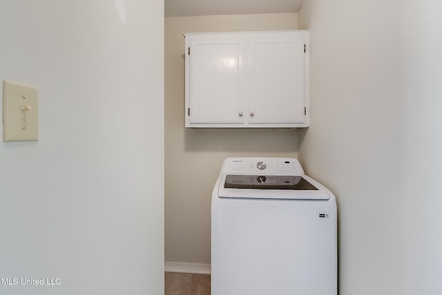 clothes washing area with washer / dryer, cabinets, light tile patterned floors, and a textured ceiling