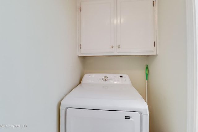 clothes washing area with washer / clothes dryer and cabinets