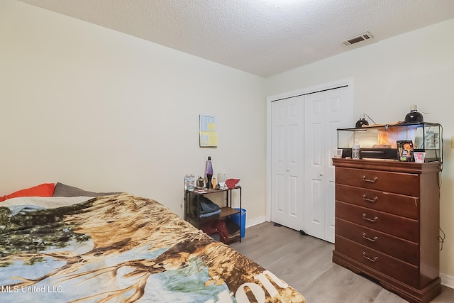 bedroom featuring a closet, a textured ceiling, and light hardwood / wood-style flooring