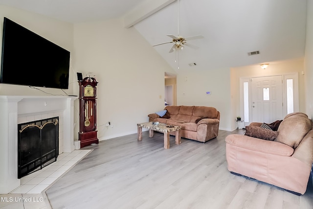 living room with a fireplace, light hardwood / wood-style floors, ceiling fan, high vaulted ceiling, and beam ceiling