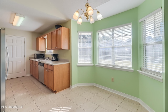 kitchen with pendant lighting, appliances with stainless steel finishes, a healthy amount of sunlight, sink, and light tile patterned flooring