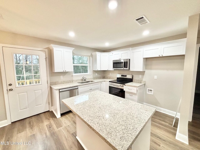 kitchen with white cabinetry, appliances with stainless steel finishes, sink, and a kitchen island