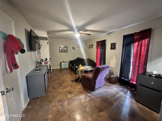 living area with a ceiling fan, baseboards, and concrete floors