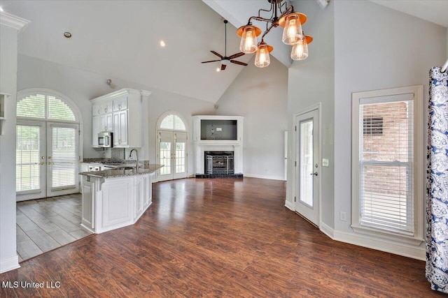 kitchen featuring high vaulted ceiling, open floor plan, french doors, stainless steel microwave, and white cabinetry