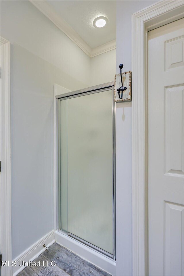 bathroom featuring baseboards, crown molding, and a stall shower