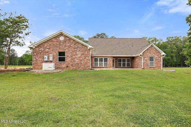 rear view of property with a lawn and brick siding
