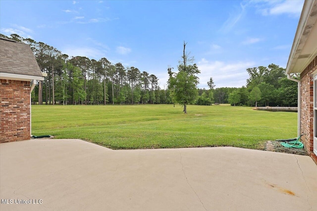view of yard featuring a forest view and a patio