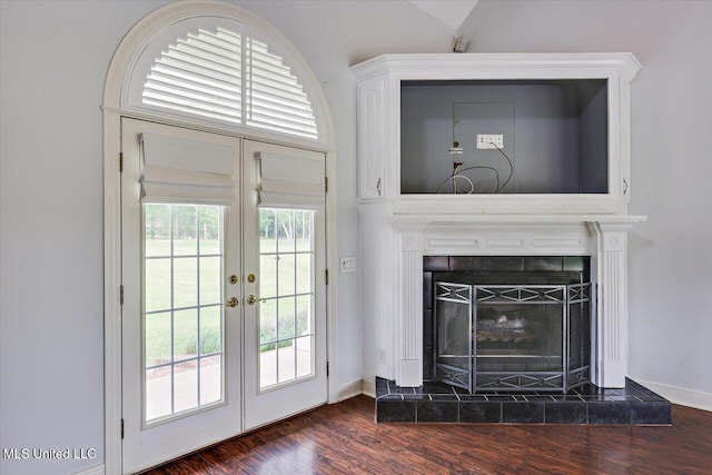 interior space featuring french doors, baseboards, a tile fireplace, and dark wood-type flooring