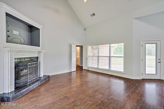 unfurnished living room with visible vents, baseboards, high vaulted ceiling, wood finished floors, and a fireplace