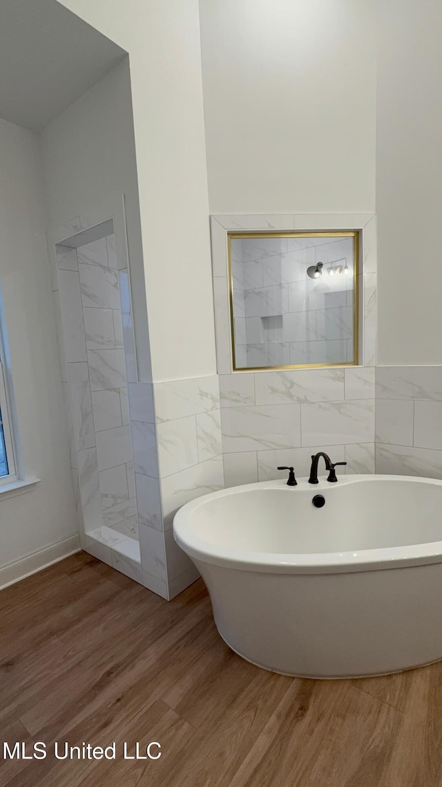 bathroom featuring wood-type flooring, shower with separate bathtub, and tile walls