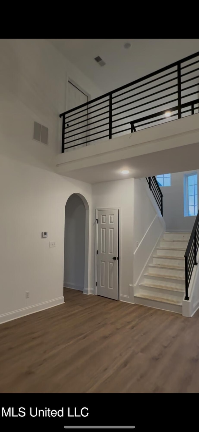 staircase with hardwood / wood-style floors and a high ceiling