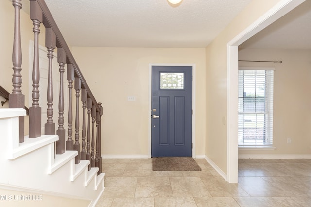 tiled entryway with a textured ceiling