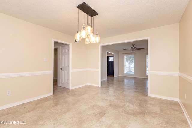 spare room with a textured ceiling and ceiling fan with notable chandelier