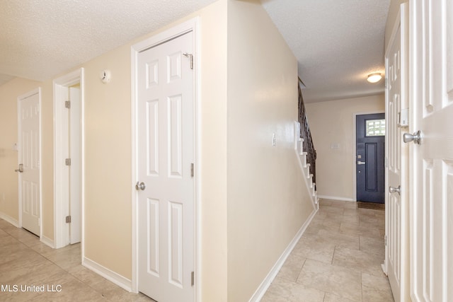 hallway featuring a textured ceiling and light tile patterned flooring