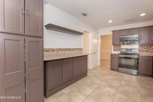 kitchen featuring backsplash, stainless steel appliances, a textured ceiling, and light stone counters