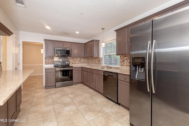 kitchen with stainless steel appliances, backsplash, sink, light stone countertops, and decorative light fixtures