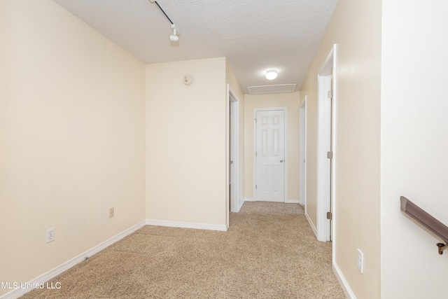 hallway with light carpet and a textured ceiling