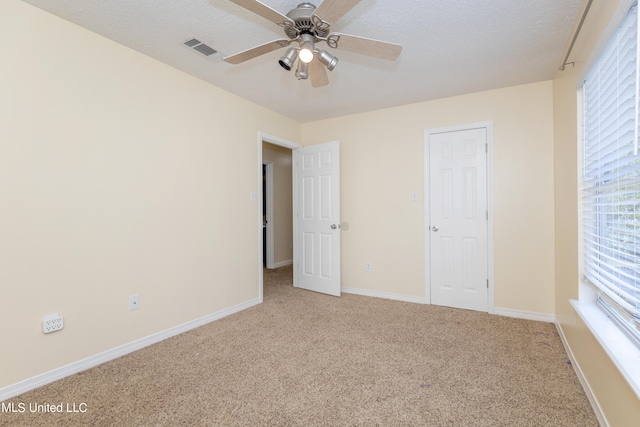 unfurnished bedroom featuring carpet flooring, a textured ceiling, and ceiling fan