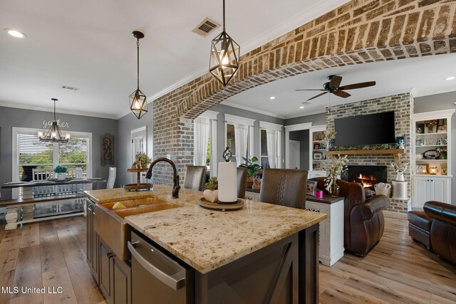 446 Newman Camp Rd, Sumrall, MS 39482 - kitchen featuring dishwasher, a kitchen island with sink, a fireplace, a sink, and crown molding