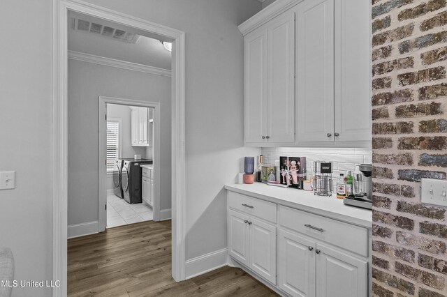 962 Glenwild Cir, Canton, MS 39046 - bar with crown molding, baseboards, wood finished floors, washer and clothes dryer, and backsplash