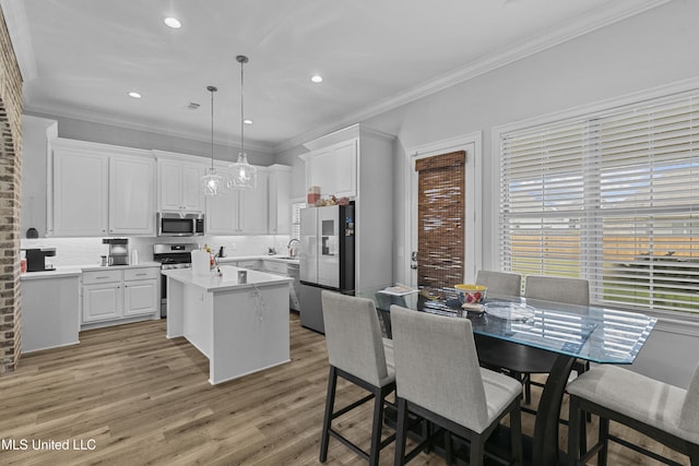 962 Glenwild Cir, Canton, MS 39046 - kitchen featuring stainless steel appliances, a kitchen island, decorative backsplash, white cabinets, and a sink