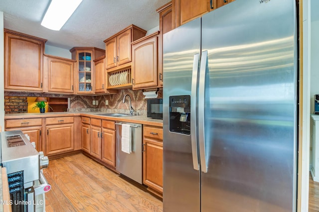109 Boggs Cir, Long Beach, MS 39560 - kitchen featuring appliances with stainless steel finishes, light wood-type flooring, light countertops, decorative backsplash, and glass insert cabinets