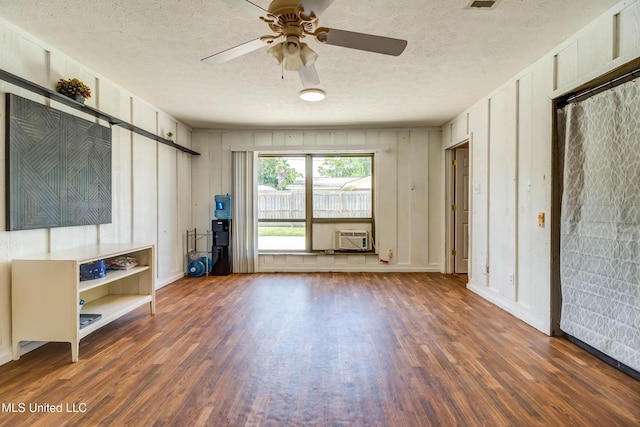 109 Boggs Cir, Long Beach, MS 39560 - unfurnished living room with wood finished floors, a ceiling fan, a textured ceiling, a decorative wall, and a wall unit AC