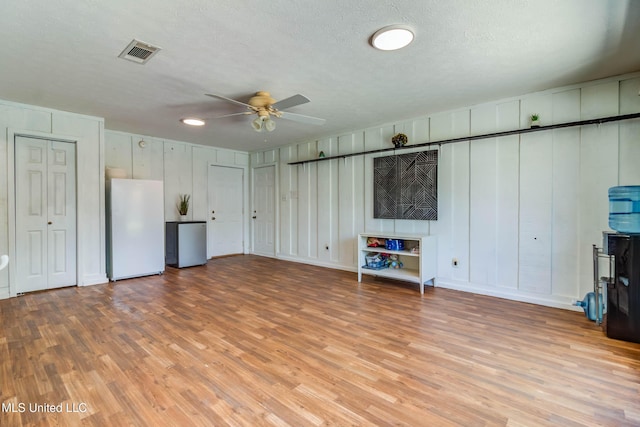 109 Boggs Cir, Long Beach, MS 39560 - unfurnished living room featuring a ceiling fan, light wood-style floors, a decorative wall, and a textured ceiling