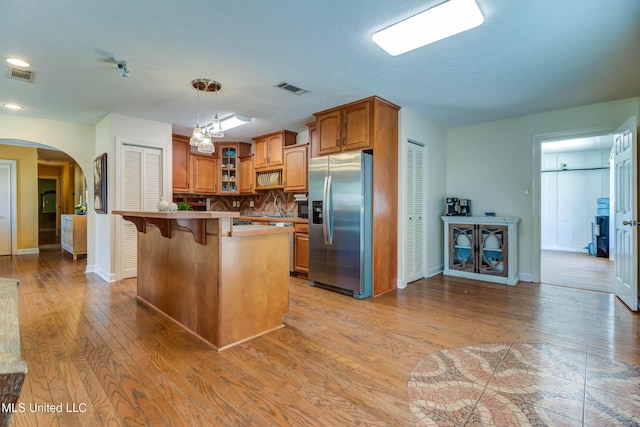 109 Boggs Cir, Long Beach, MS 39560 - kitchen with stainless steel fridge, a kitchen bar, light wood-style floors, and glass insert cabinets