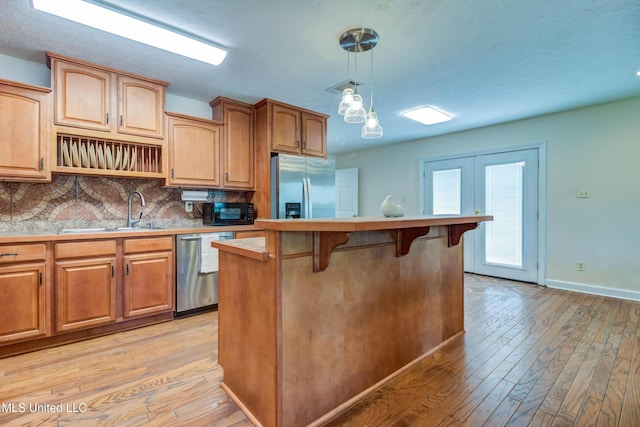 109 Boggs Cir, Long Beach, MS 39560 - kitchen featuring appliances with stainless steel finishes, light wood finished floors, a breakfast bar area, and tasteful backsplash