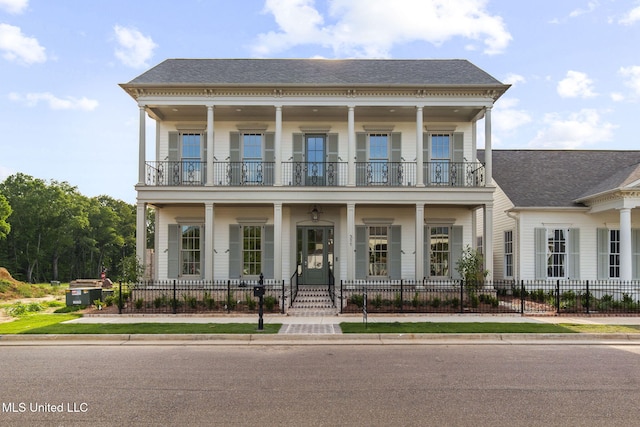 view of front of property with a balcony, a porch, a fenced front yard, and a shingled roof