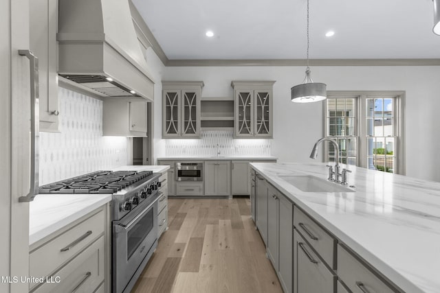 kitchen featuring a sink, premium range hood, stainless steel stove, gray cabinets, and recessed lighting