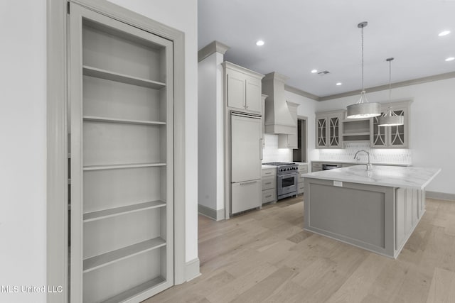 kitchen featuring premium appliances, glass insert cabinets, backsplash, hanging light fixtures, and recessed lighting