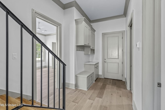 mudroom featuring light wood-style floors, baseboards, and crown molding