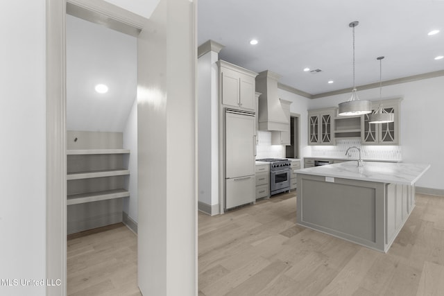 kitchen with premium appliances, light wood finished floors, glass insert cabinets, decorative backsplash, and recessed lighting