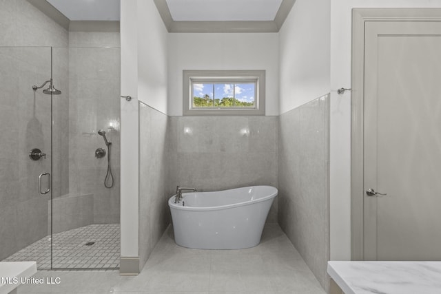 bathroom featuring a stall shower, a soaking tub, tile walls, and tile patterned flooring