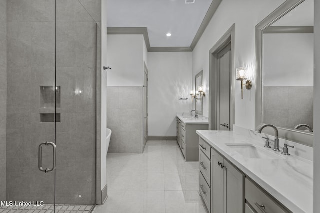 full bathroom featuring a stall shower, two vanities, a freestanding tub, tile patterned flooring, and crown molding