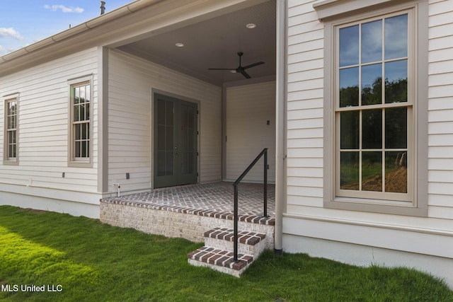 doorway to property featuring a ceiling fan, a yard, and a patio