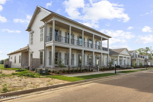 neoclassical home featuring a balcony, a porch, and central AC