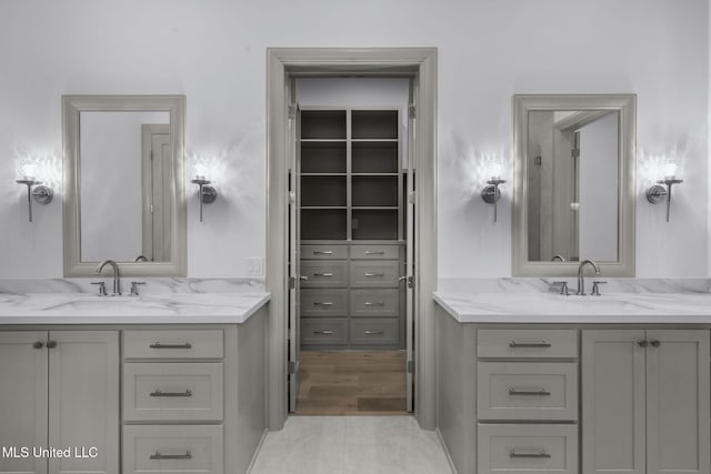 bathroom featuring two vanities and a spacious closet