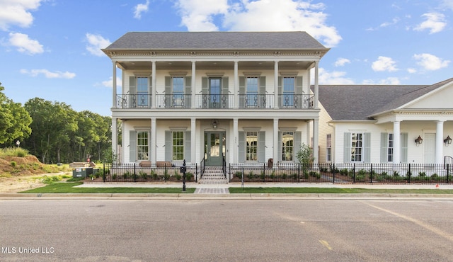 greek revival house with a balcony, a fenced front yard, a porch, and a shingled roof