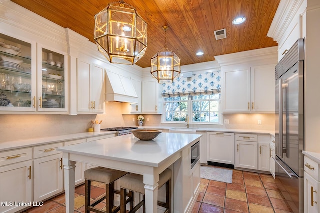 102 Melrose Montebello Pkwy, Natchez, MS 39120 - kitchen featuring wooden ceiling, built in appliances, a chandelier, custom exhaust hood, and white cabinetry