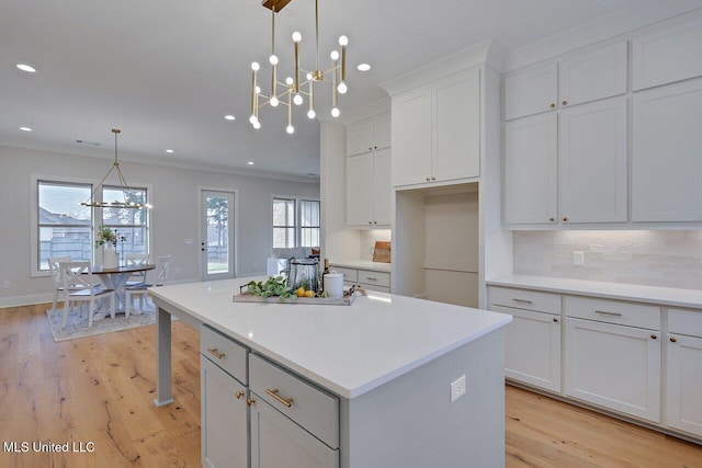 kitchen featuring a chandelier, white cabinetry, a kitchen island, decorative light fixtures, and tasteful backsplash