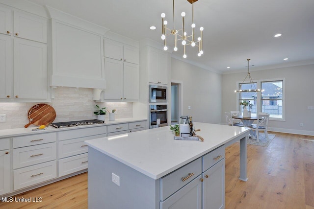 kitchen featuring stainless steel appliances, white cabinets, decorative light fixtures, a chandelier, and a kitchen island