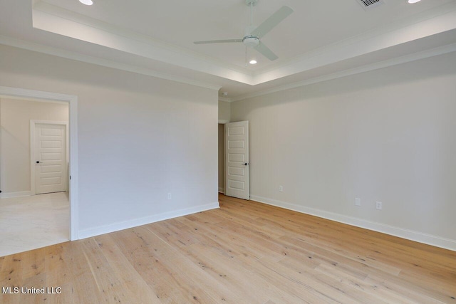 empty room featuring ceiling fan, crown molding, light hardwood / wood-style floors, and a raised ceiling