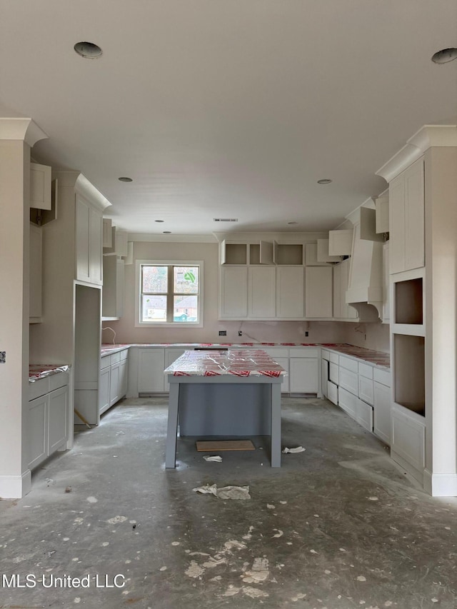 kitchen featuring white cabinetry, a kitchen island, a breakfast bar area, and custom range hood