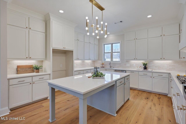 kitchen with light hardwood / wood-style flooring, hanging light fixtures, a breakfast bar, and white cabinets