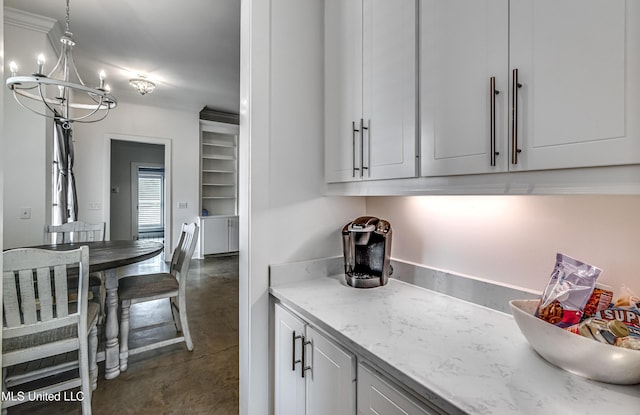 625 Wild Horse Ln, Brandon, MS 39042 - kitchen featuring concrete flooring, a chandelier, white cabinetry, light stone countertops, and pendant lighting